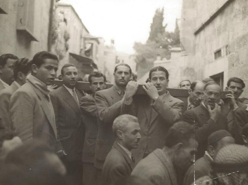 CNS photo/courtesy Kamar family A photo shows Mousa Kamar's father, Youssef Kamar, right front, carrying the large wooden cross during the Good Friday procession on the Via Dolorosa in Jerusalem's Old City. (CNS photo/courtesy Kamar family)